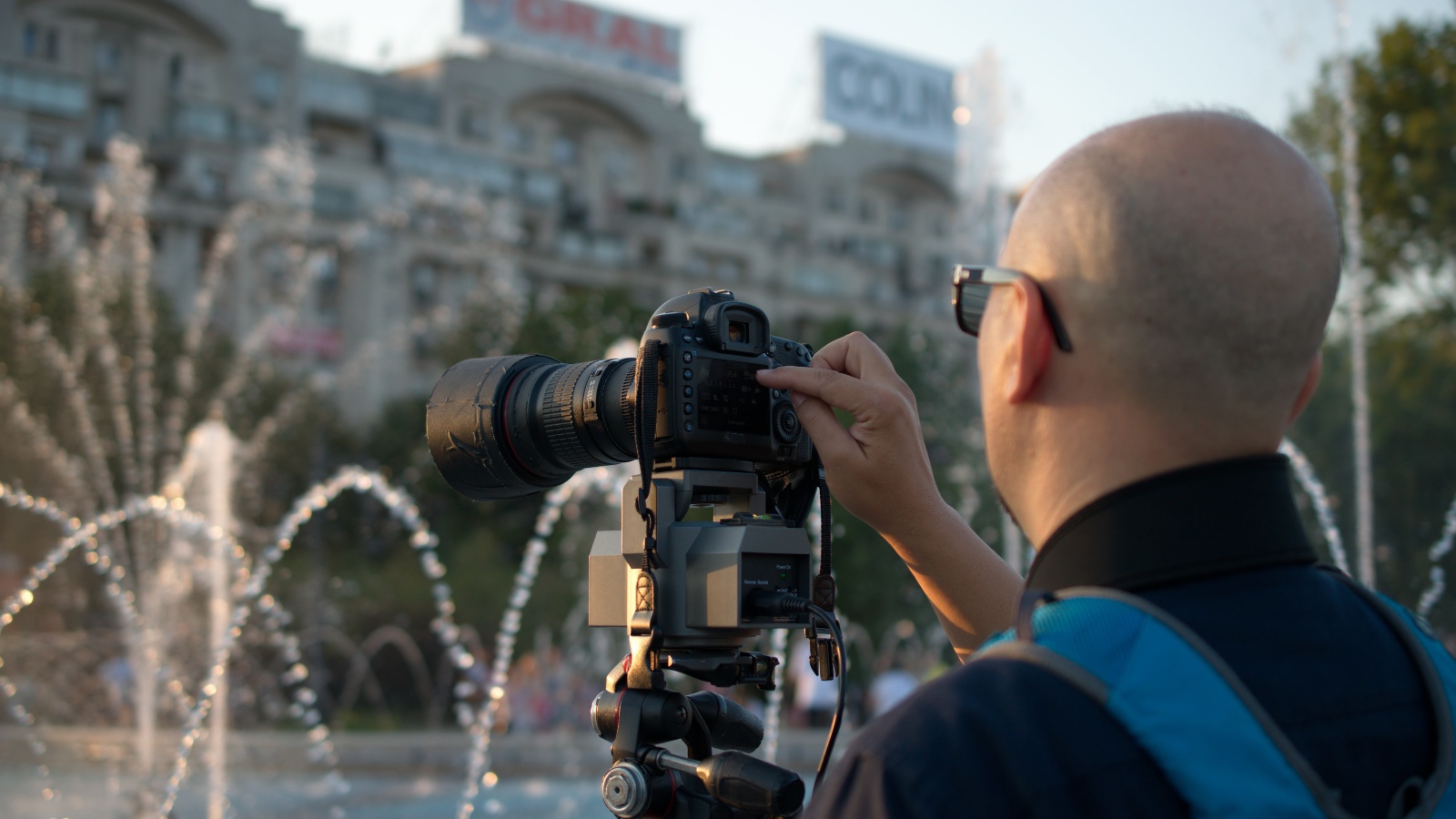 Мужчина снимает на камеру фонтан в парке