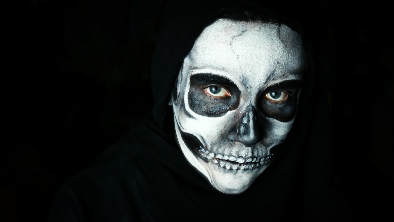 Мужчина в черном наряде с гримом на лице на Хэллоуин