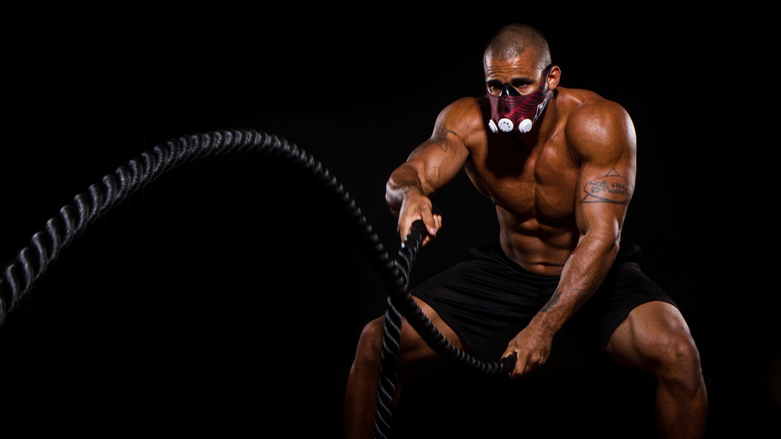 Накаченный мужчина в маске с канатом в руках 