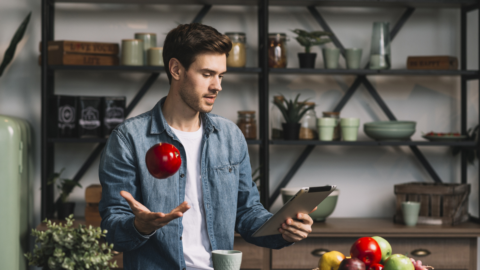 Молодой мужчина с планшетом и яблоком в руке 