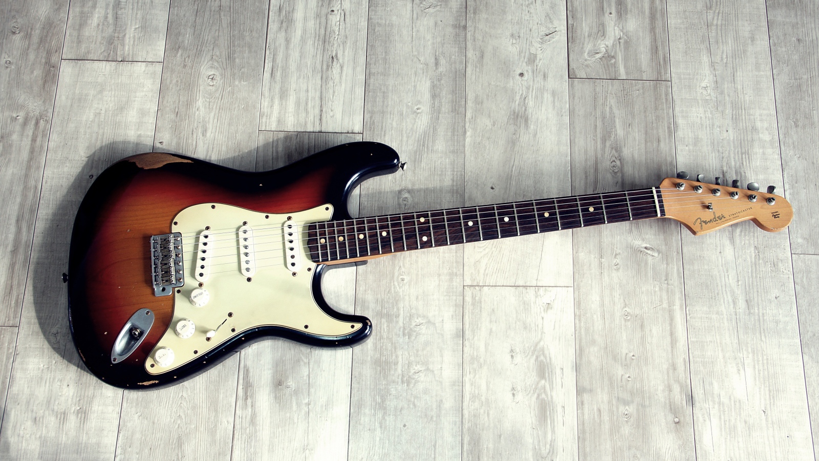 Электрогитара лежит на деревянном полу