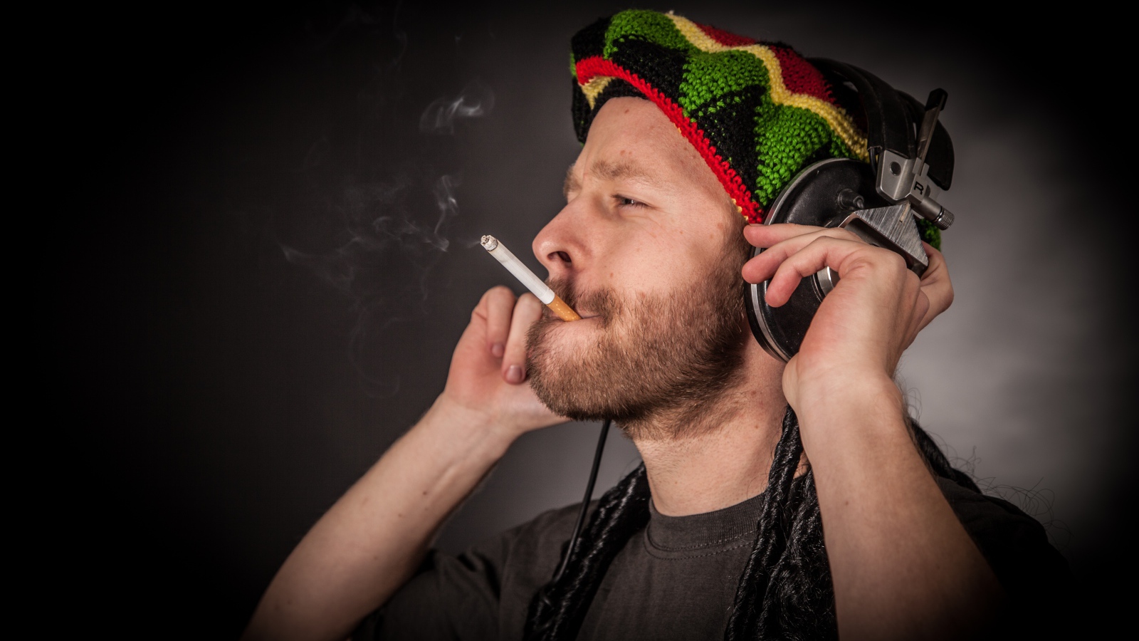 Мужчина растаман в наушниках с сигаретой 