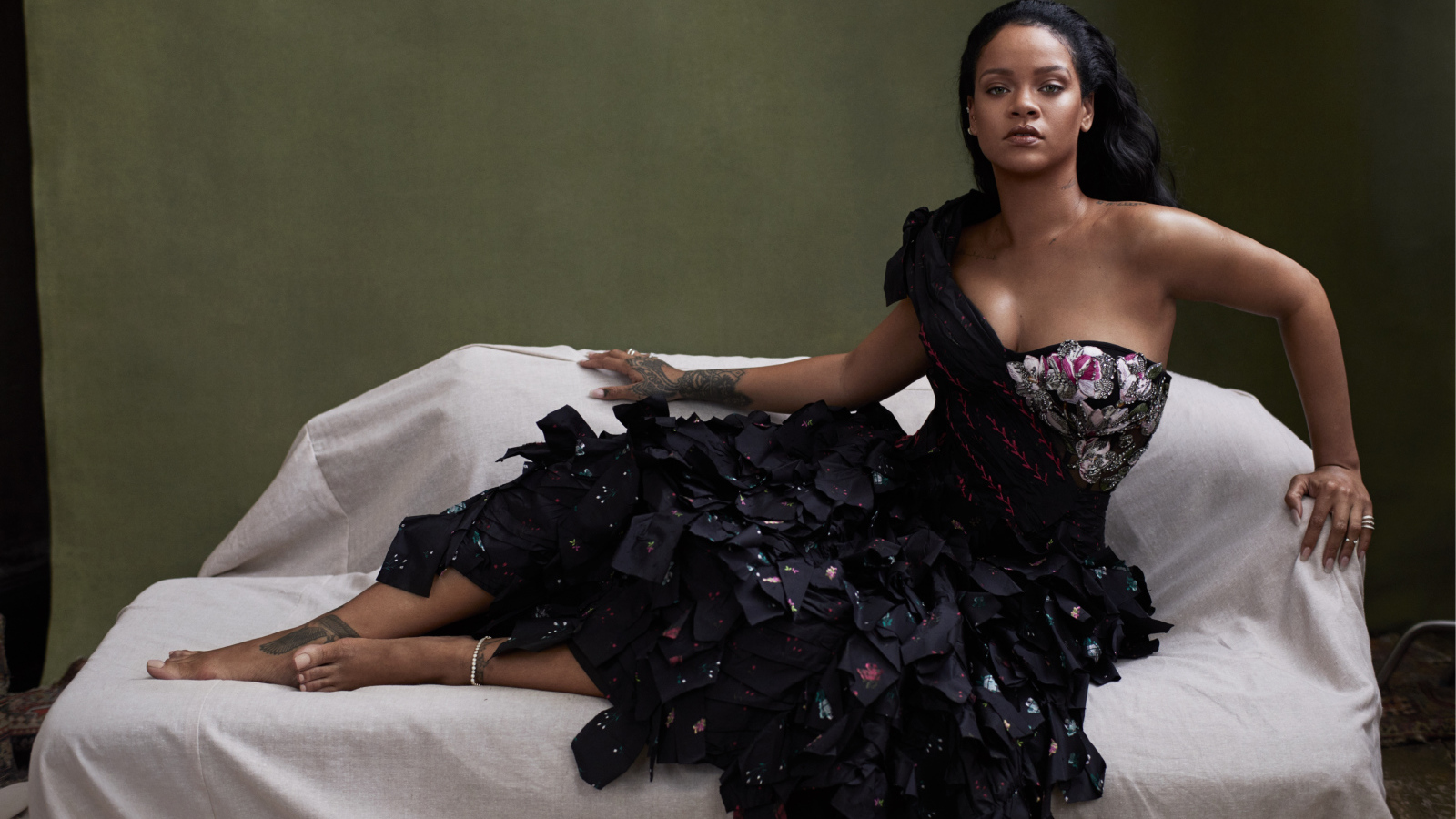 Певица Рианна в черном платье на диване 