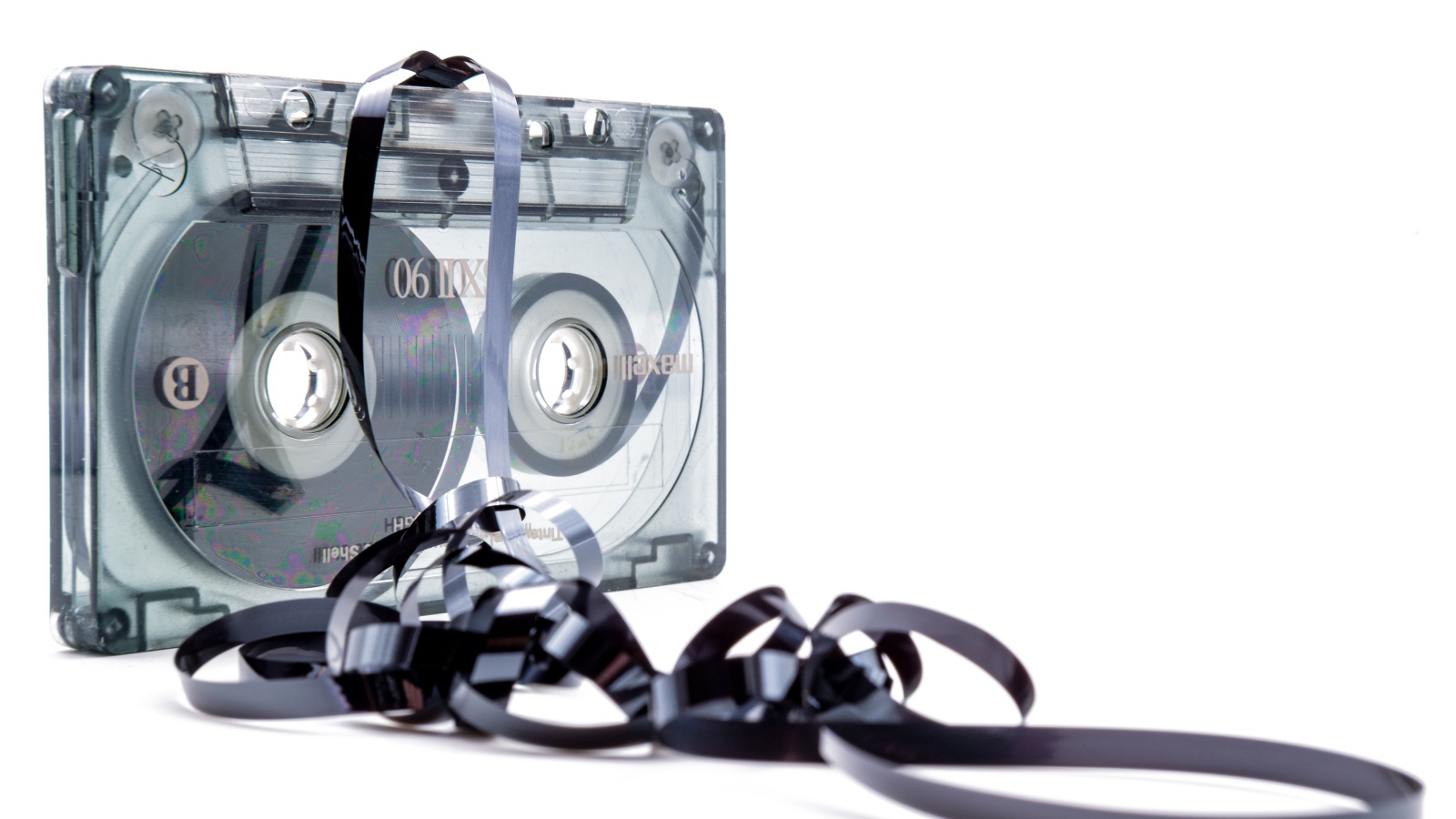 Магнитофонная кассета в размотанной пленкой на белом фоне