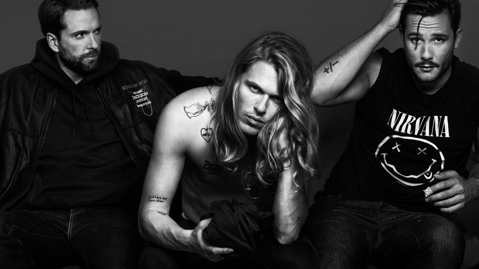 Трио Kris Kross Amsterdam в костюмах на сером фоне