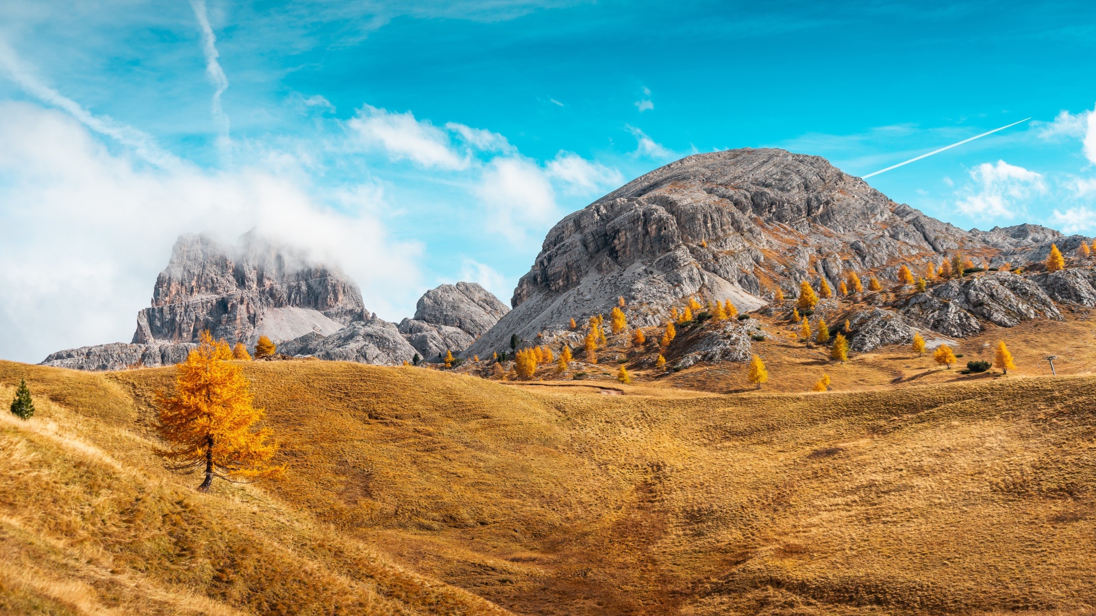 Холмы с сухой травой у гор под голубым небом