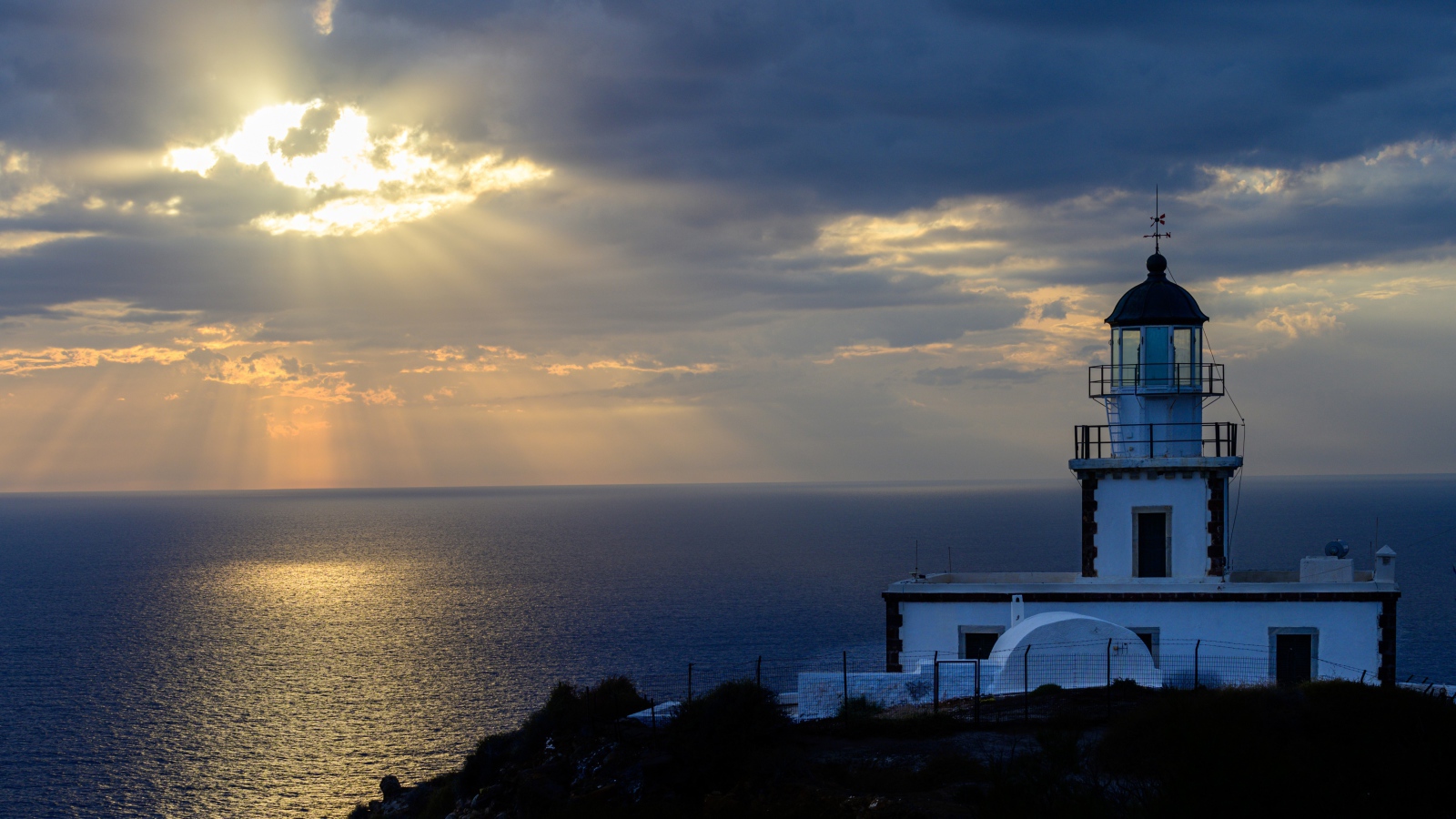 Белый маяк на берегу в лучах солнца у моря 