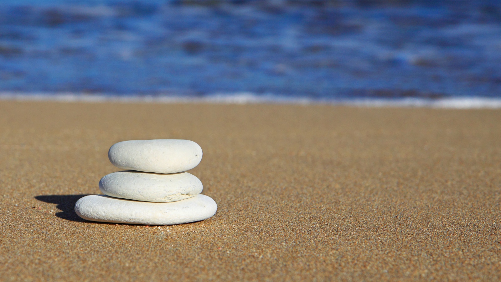 Круглые белые камни на желтом песке 