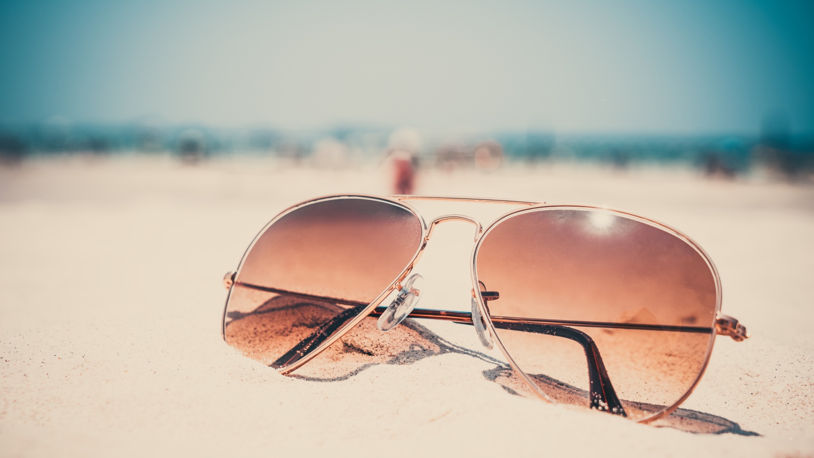 Солнечные очки лежат на горячем песке 