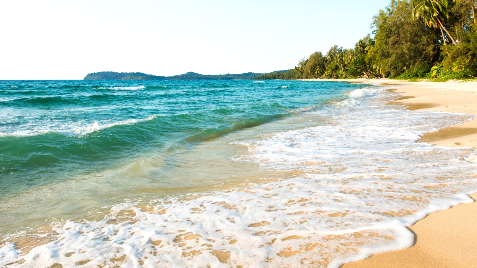 Белая пена на желтом песке тропического пляжа 