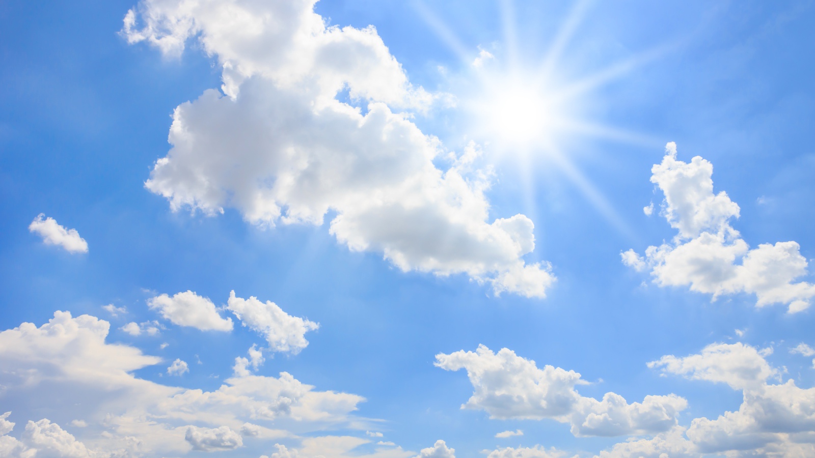 Яркое солнце в голубом небе с белыми облаками