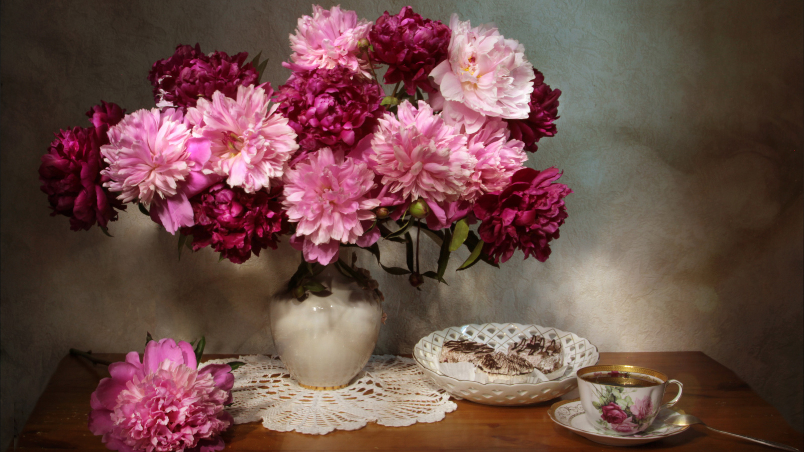 Большой букет розовых пионов в вазе на столе 