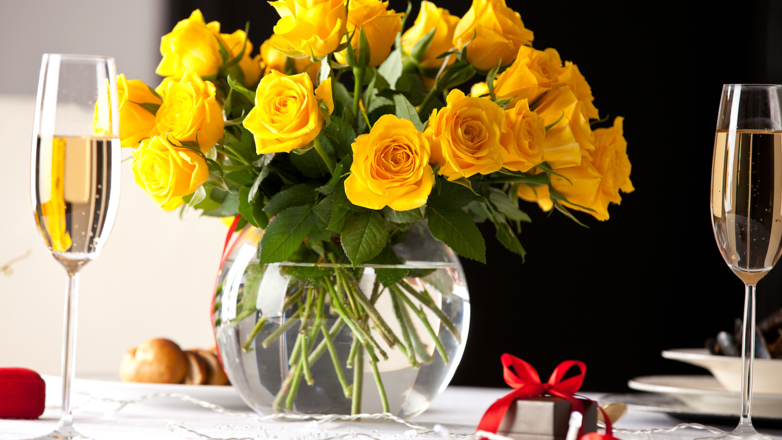 Большой букет желтых роз в вазе на столе с фужерами