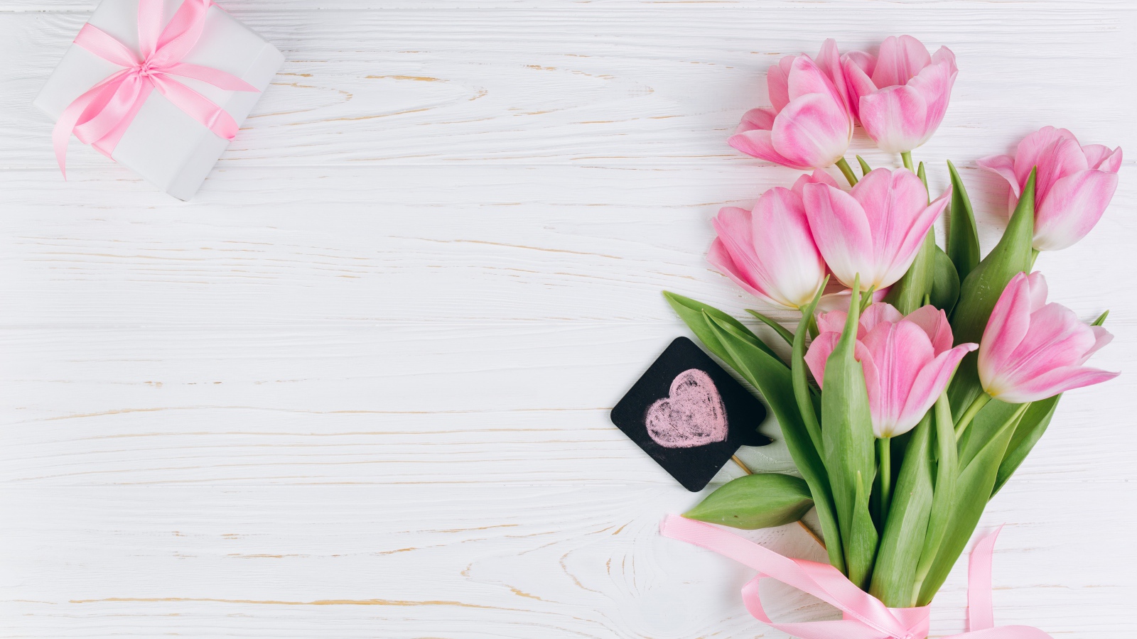 Красивый букет розовых тюльпанов с подарком на сером фоне
