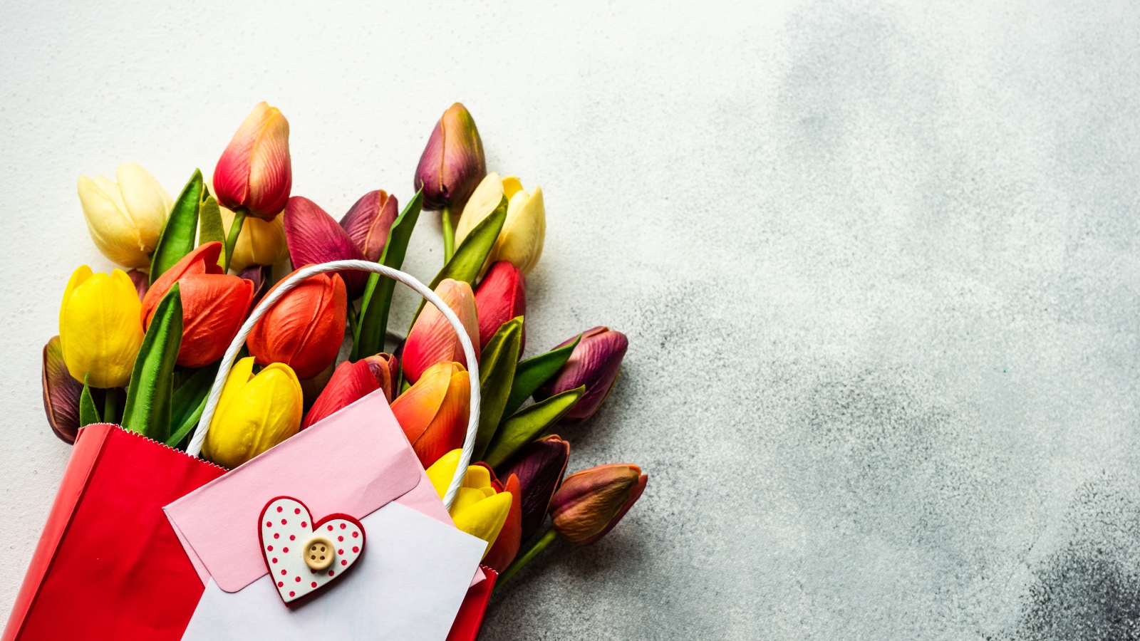 Букет разноцветных тюльпанов с письмом на сером фоне