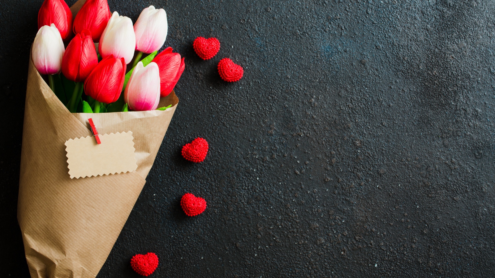 Букет тюльпанов в бумаге на сером фоне с красными сердечками
