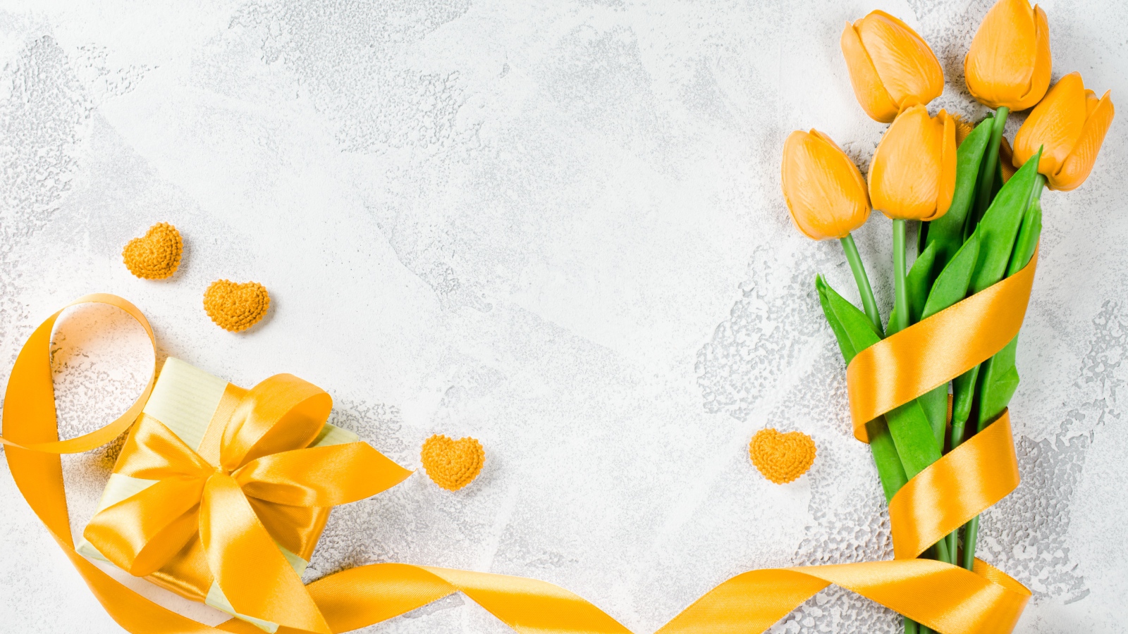 Букет желтых тюльпанов с лентой и подарком на сером фоне