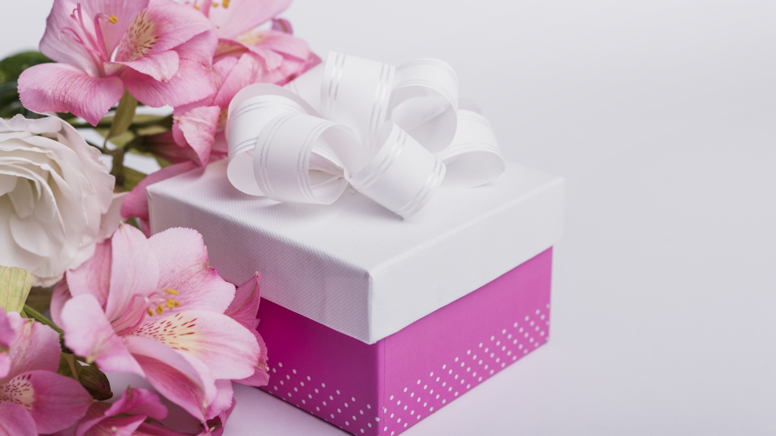 Розовые цветы альстромерии на сером фоне с подарком 