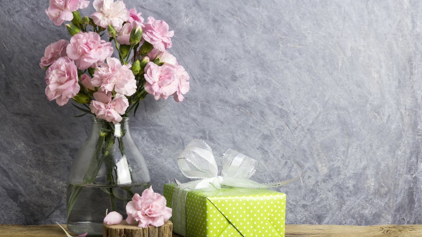 Розовые гвоздики с подарком на сером фоне