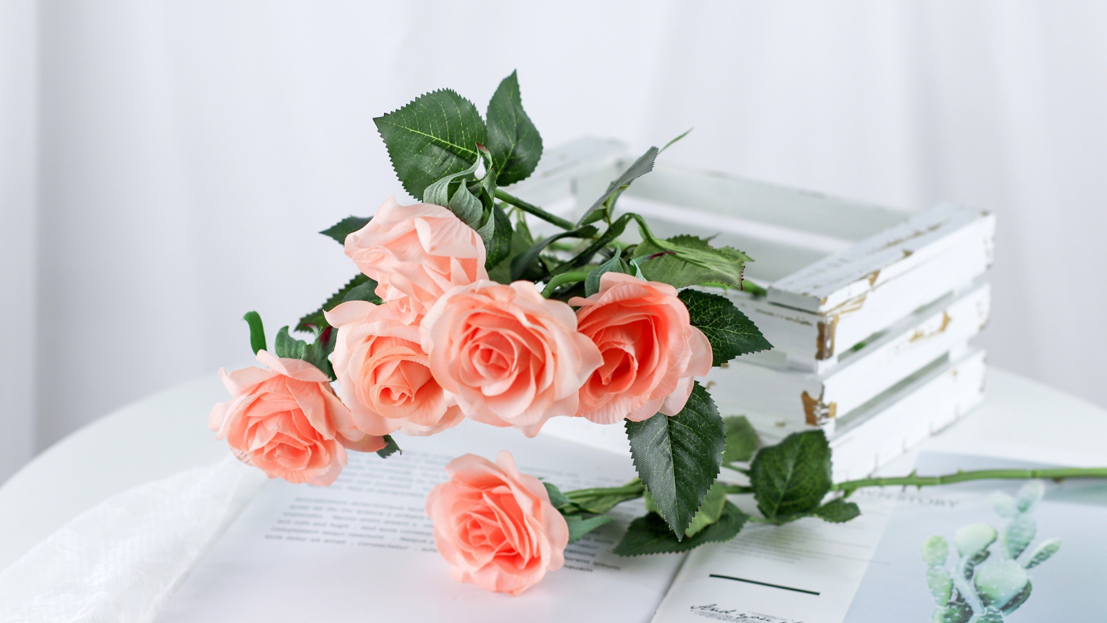 Розовые цветы лежат на столе на журнале
