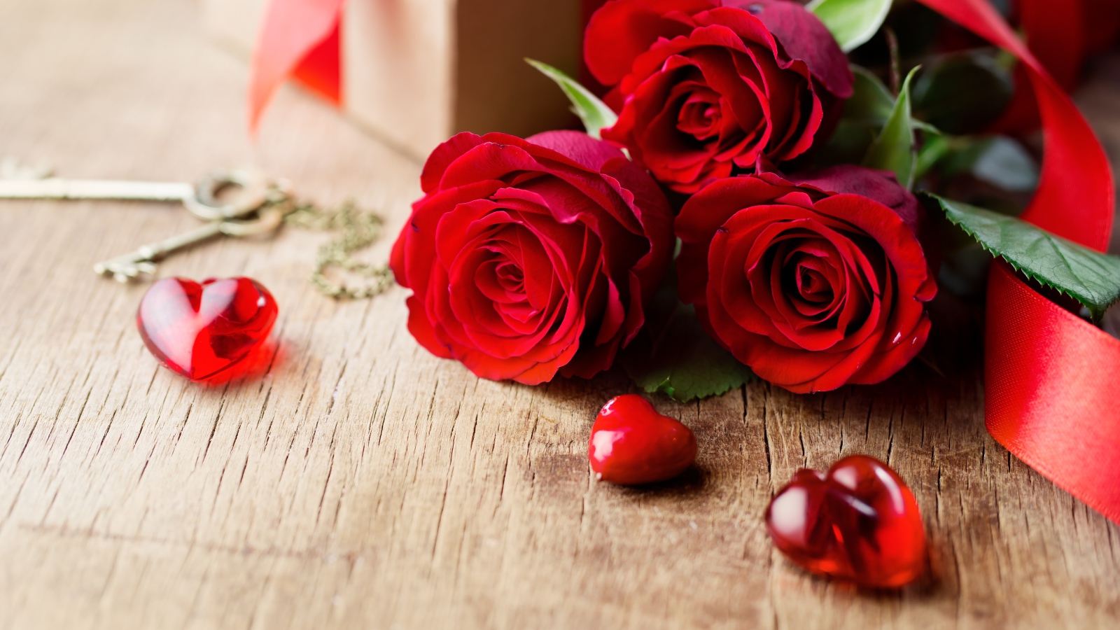 Три красивые красные розы на столе с сердечками и ключами