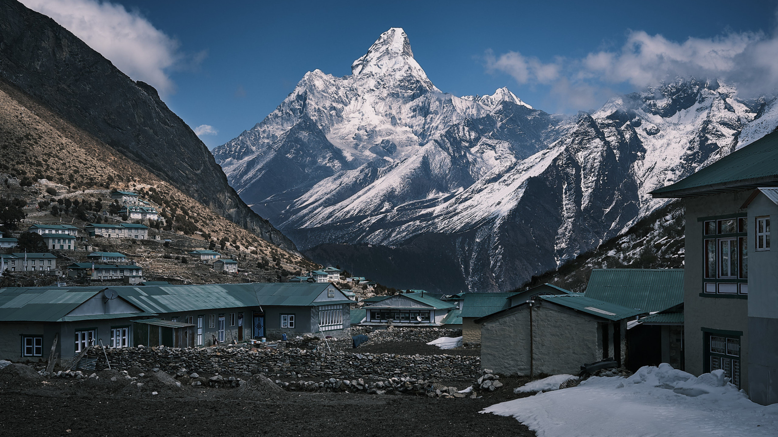 Поселок на фоне заснеженных гор под голубым небом 