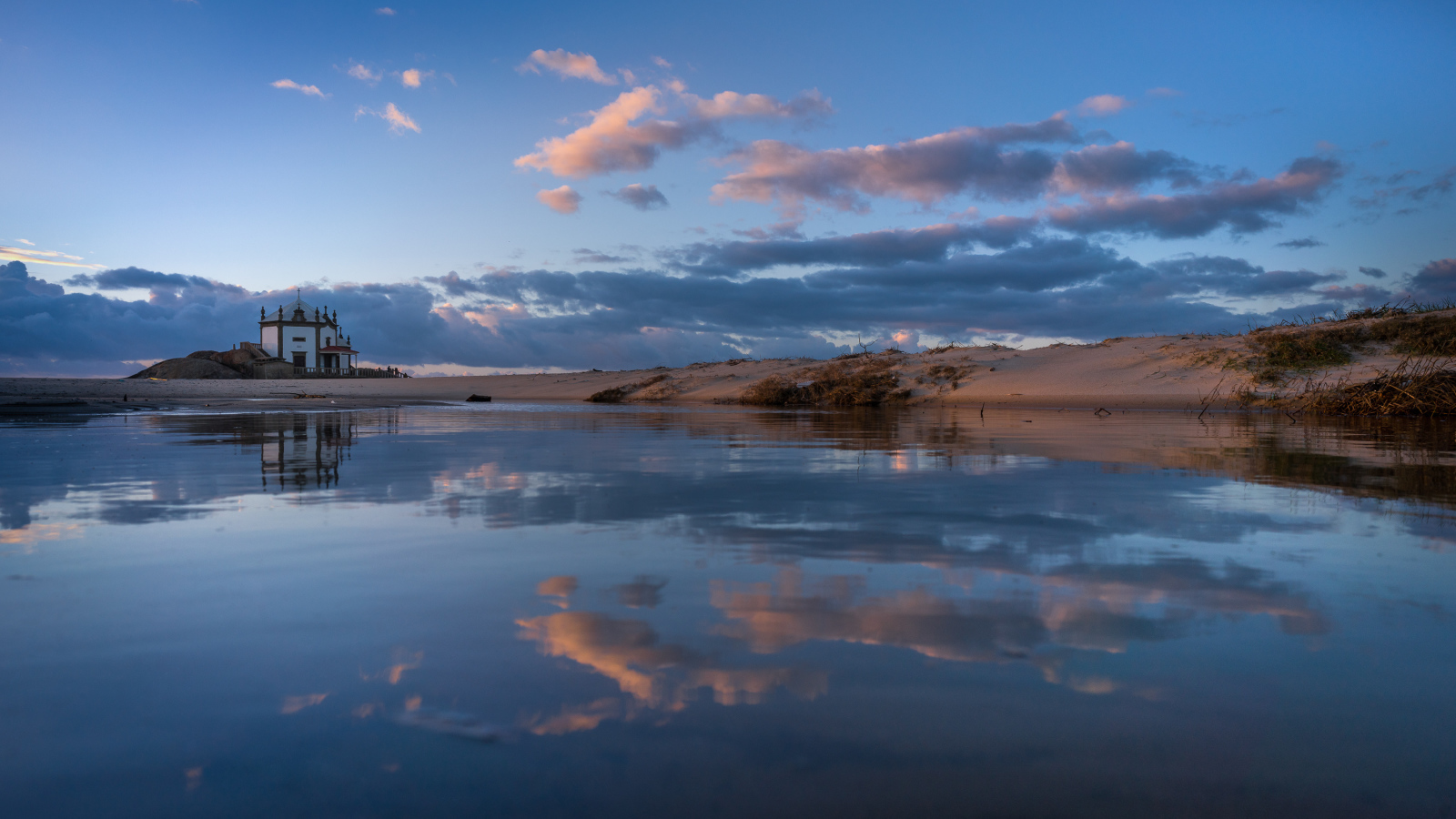 Облака отражаются в спокойной воде озера 