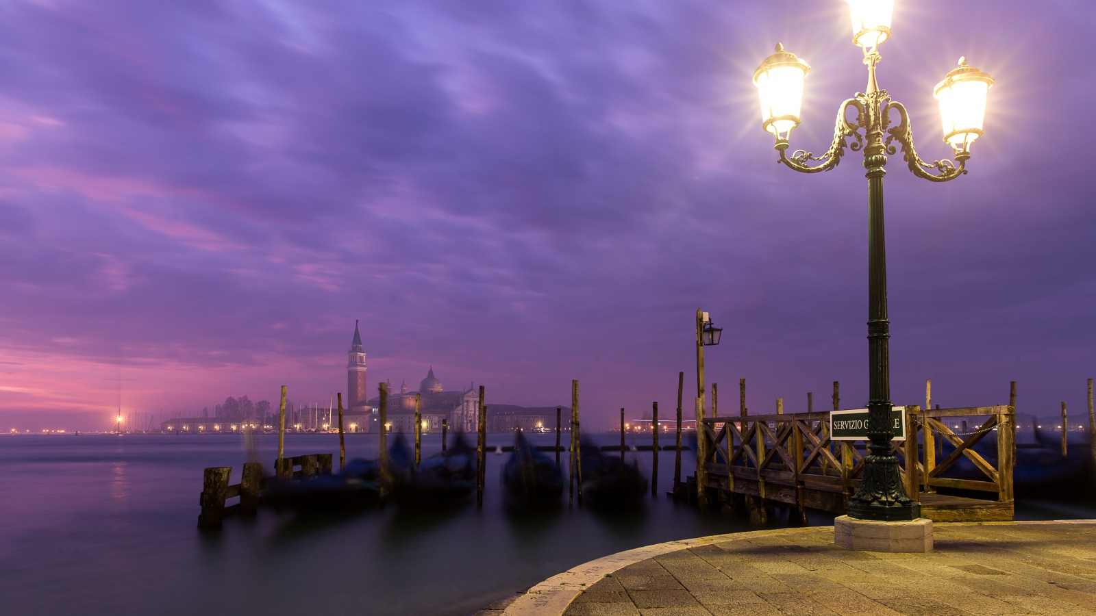 Зажженный фонарь на берегу реки ночью 