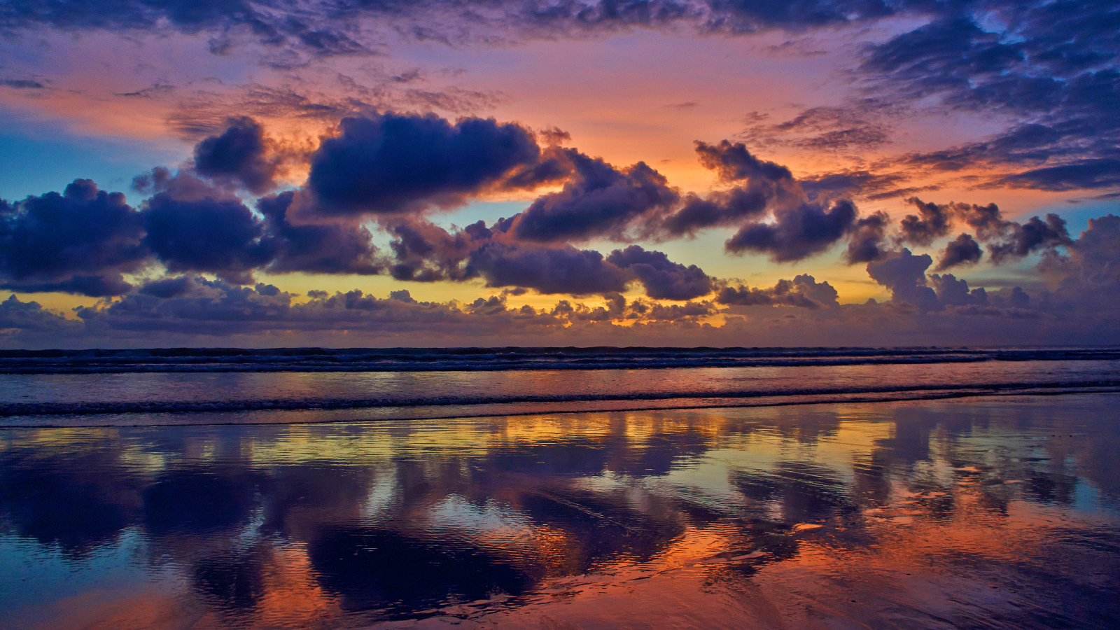 Black clouds reflected in sea water at sunset.