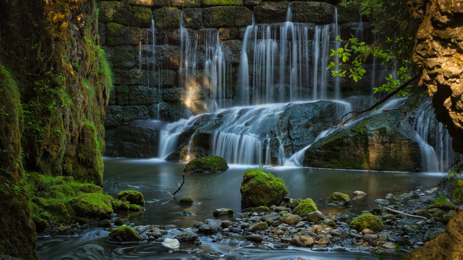 Водопад пробивается сквозь покрытые мхом камни 