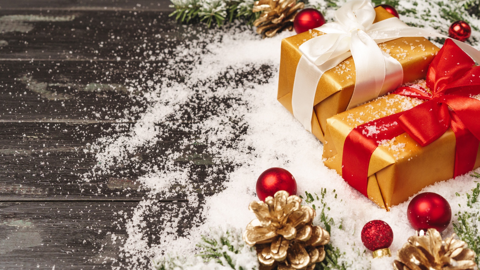 Два новогодних подарка на столе с еловыми ветками 