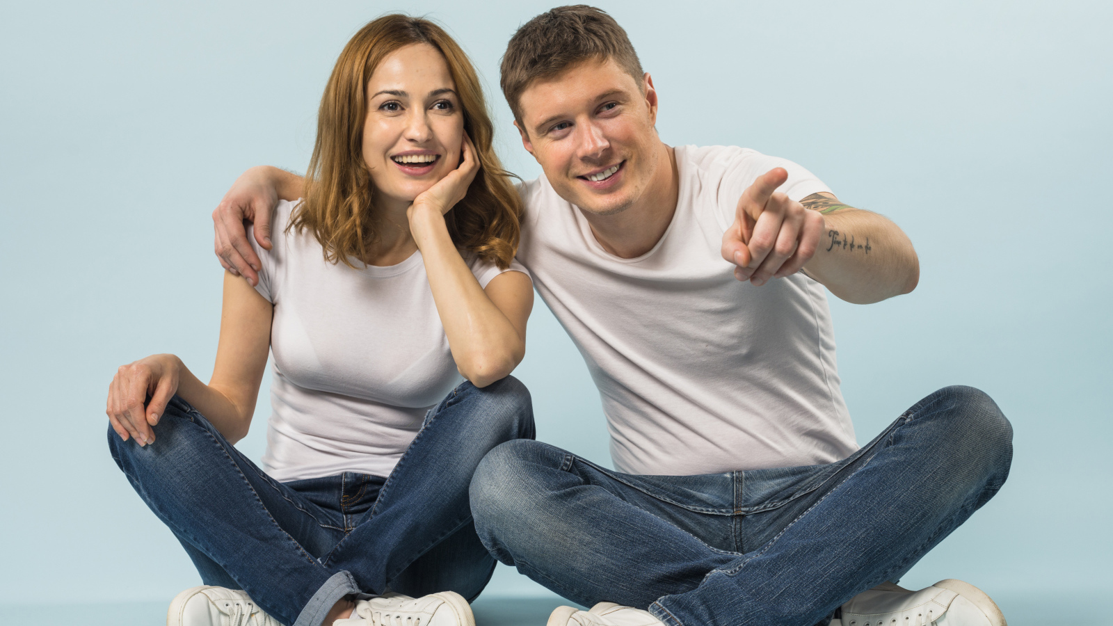 Мужчина и девушка сидят на полу на голубом фоне