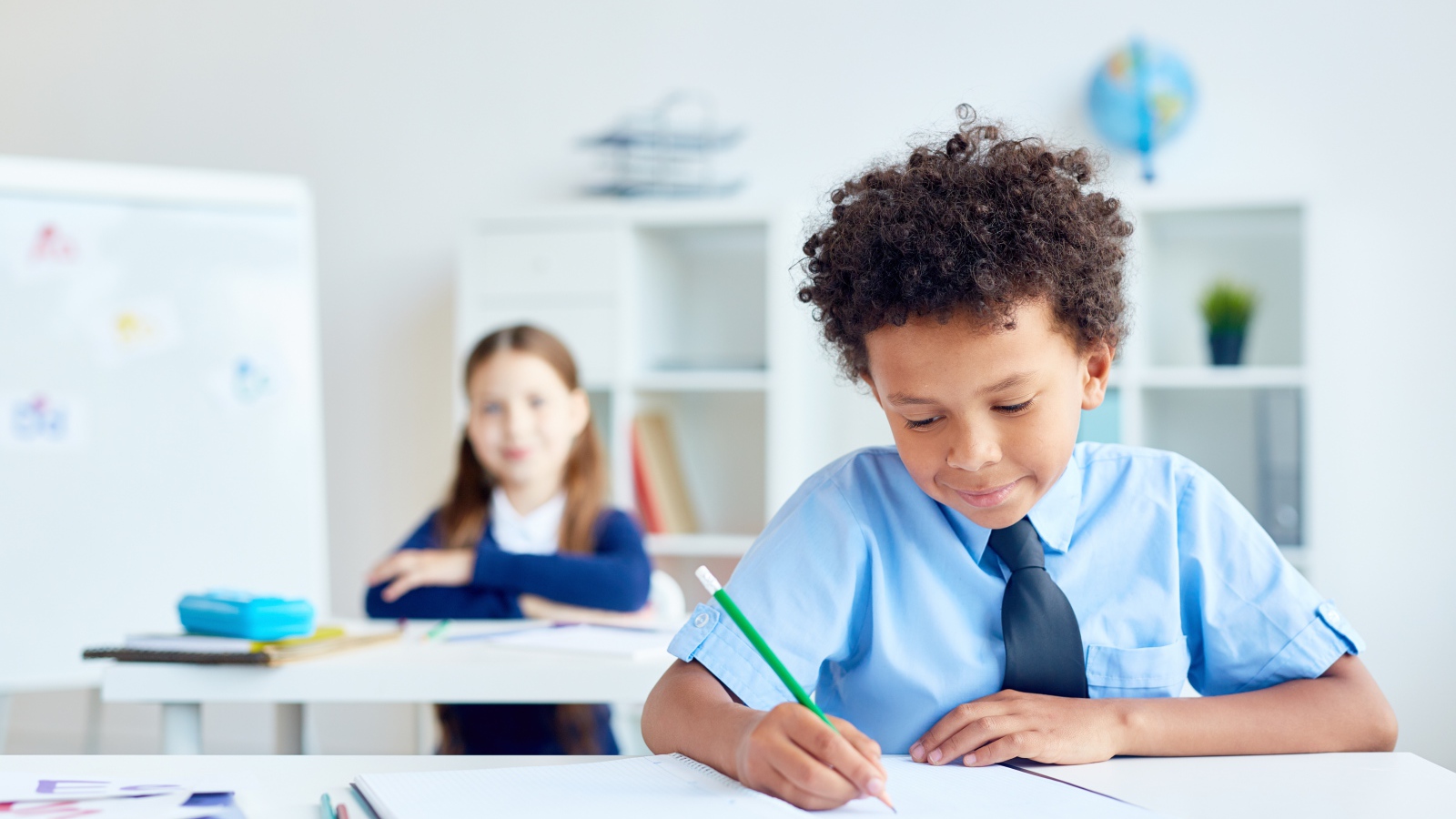 Маленький мальчик сидит за партой в классе