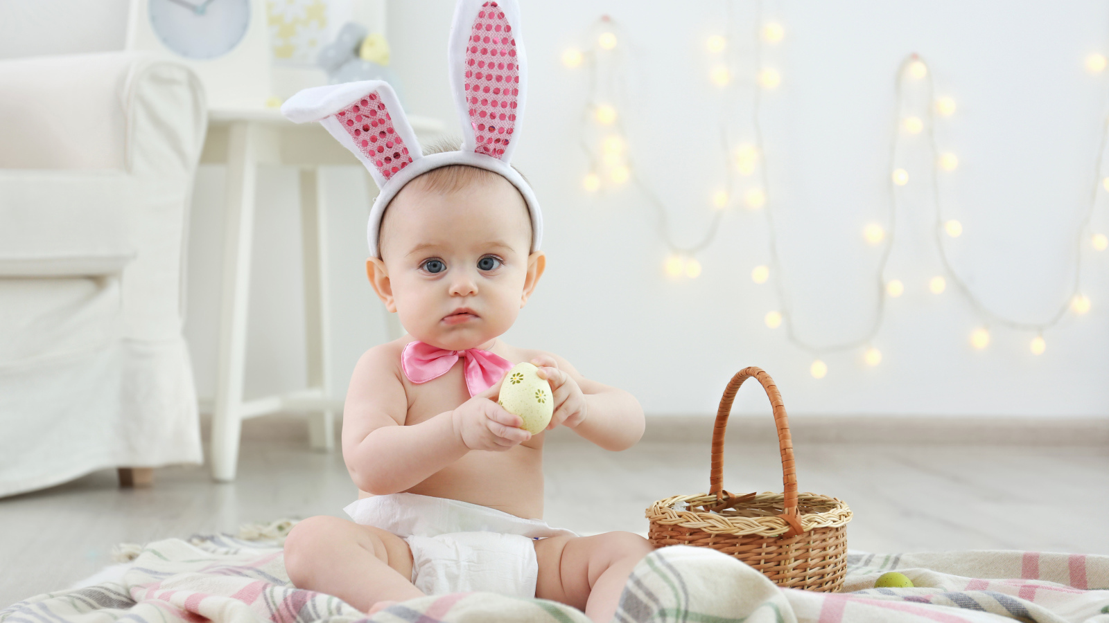 Милый ребенок с ушками на голове сидит пасхальными яйцами