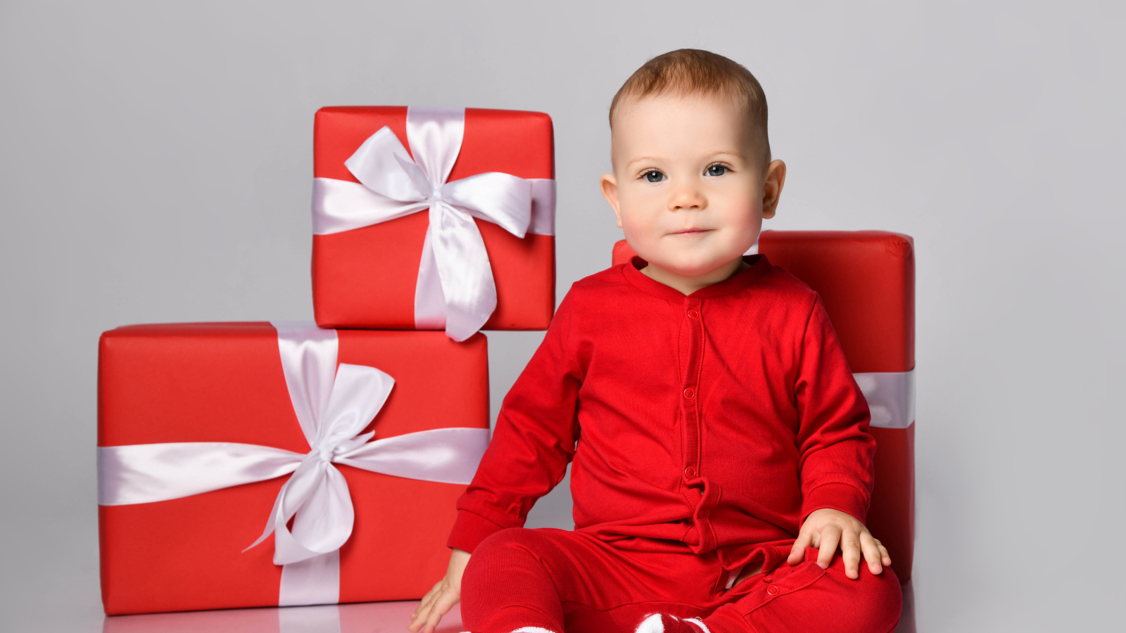 Милый малыш в красном костюме с подарками на новый год 