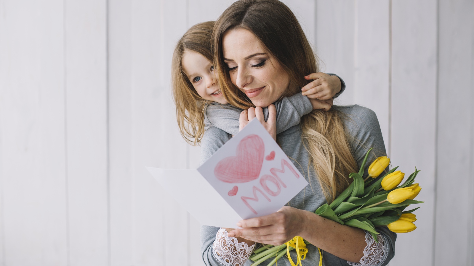 Маленькая девочка подарила маме открытку и букет тюльпанов