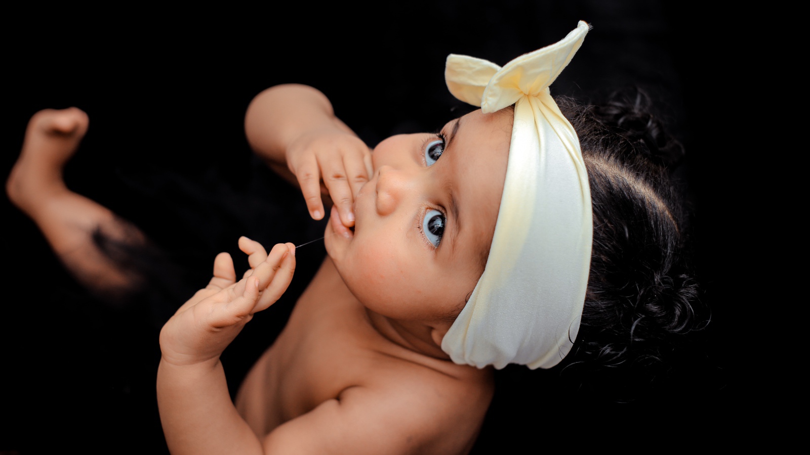 Маленькая девочка с повязкой на голове на черном фоне