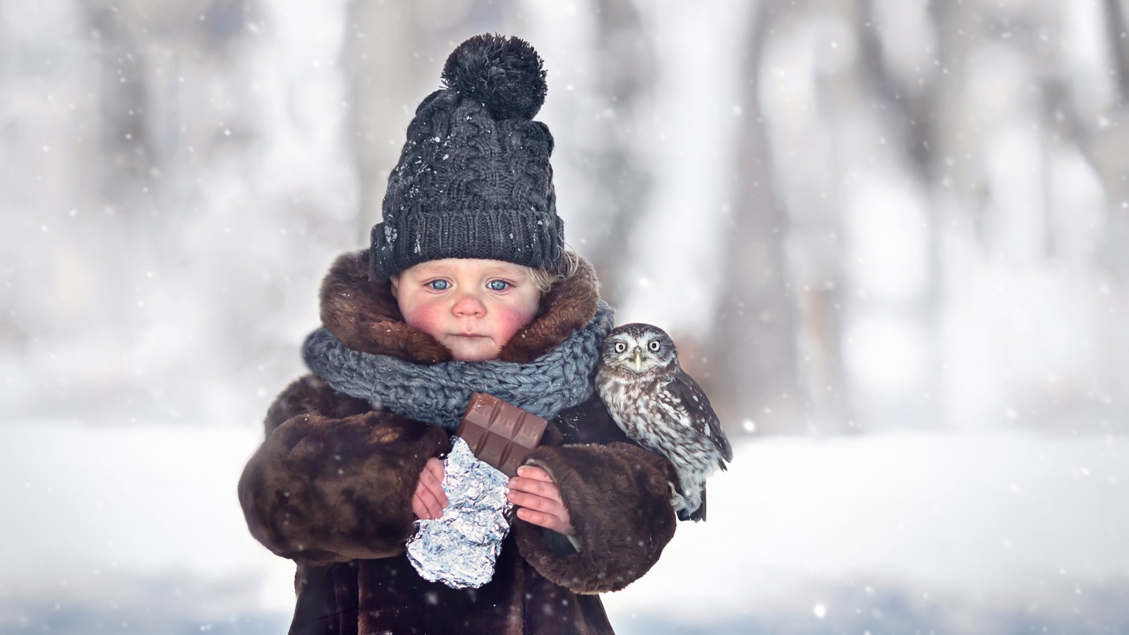 Маленькая девочка с шоколадкой в руках на улице зимой