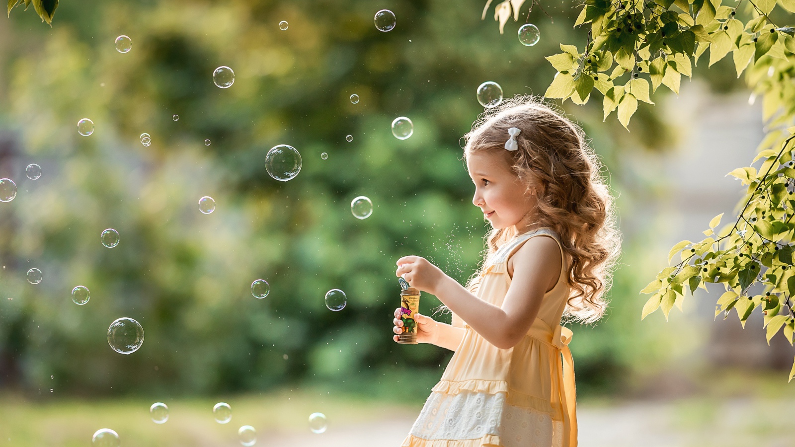 Маленькая девочка с мыльными пузырями в саду 