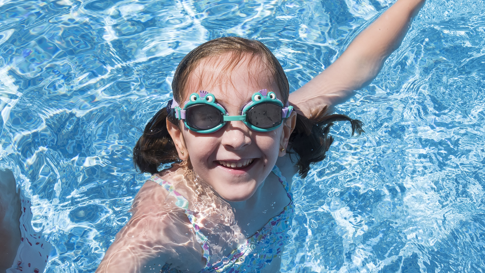Маленькая улыбающаяся девочка в очках в бассейне 
