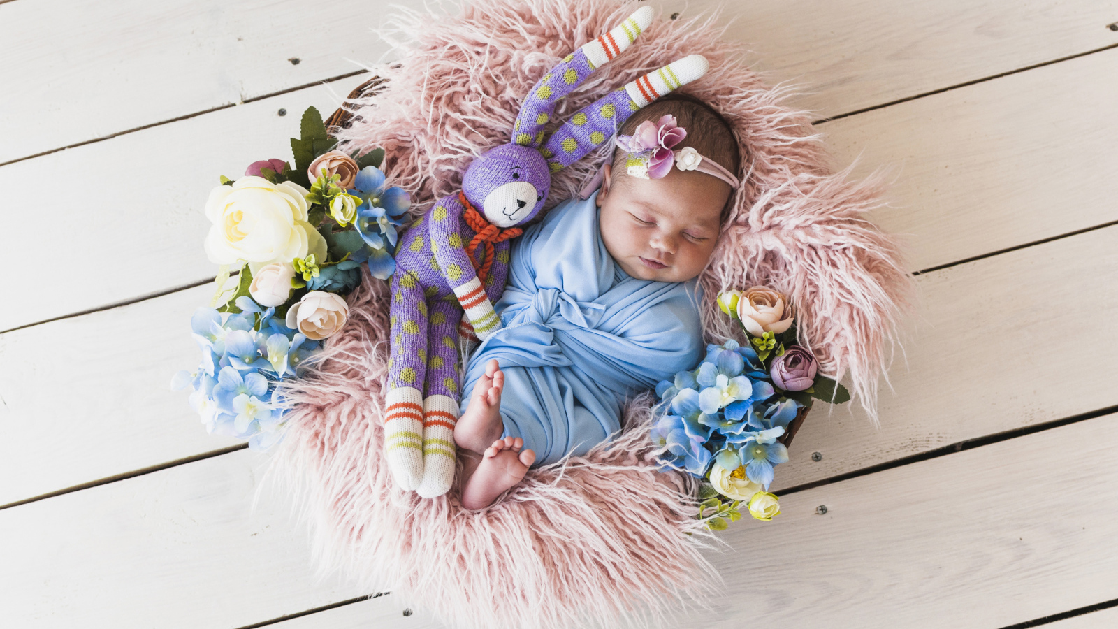 Спящий грудной ребенок с игрушкой в корзине 