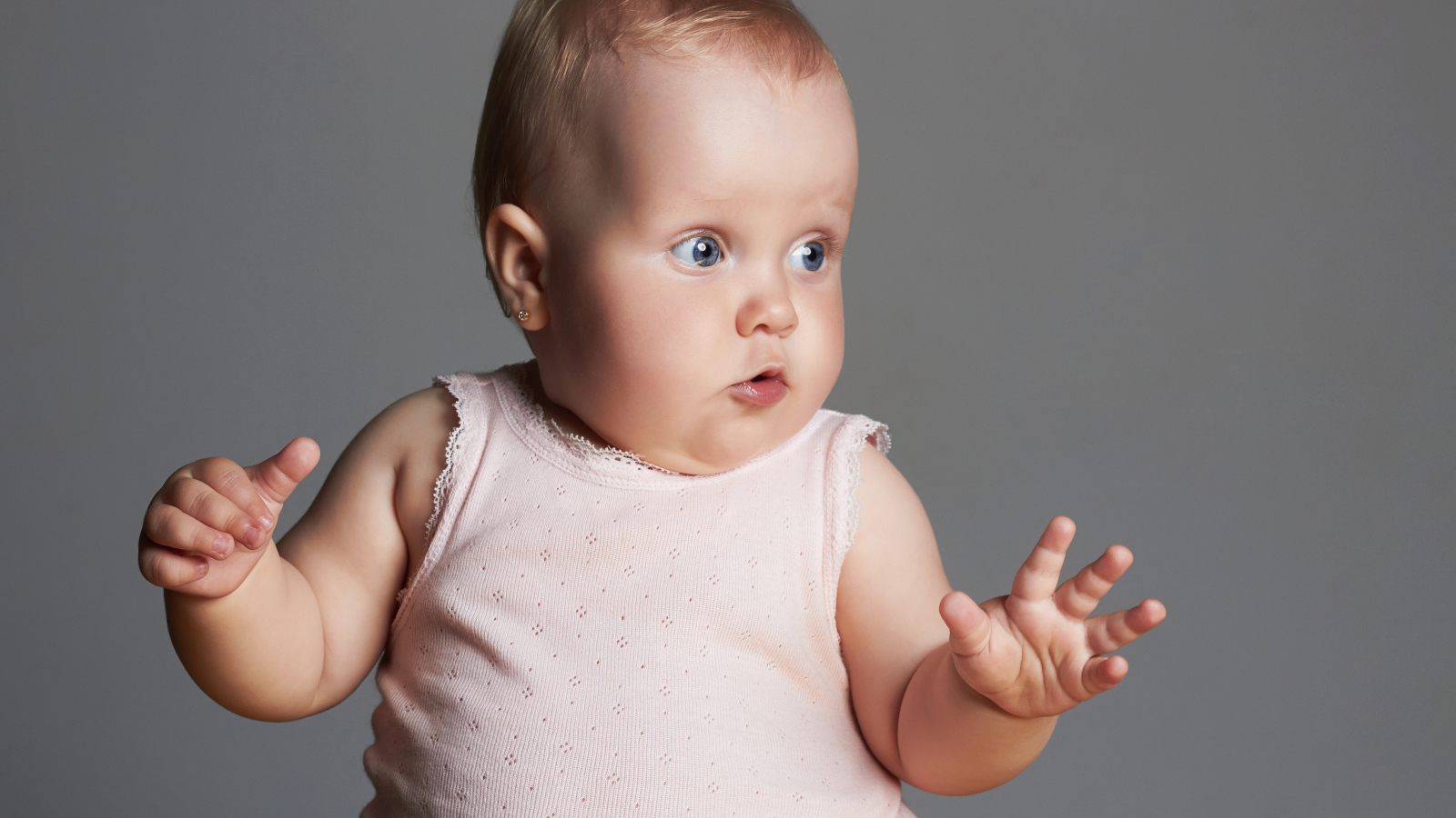 Удивленный маленький ребенок на сером фоне