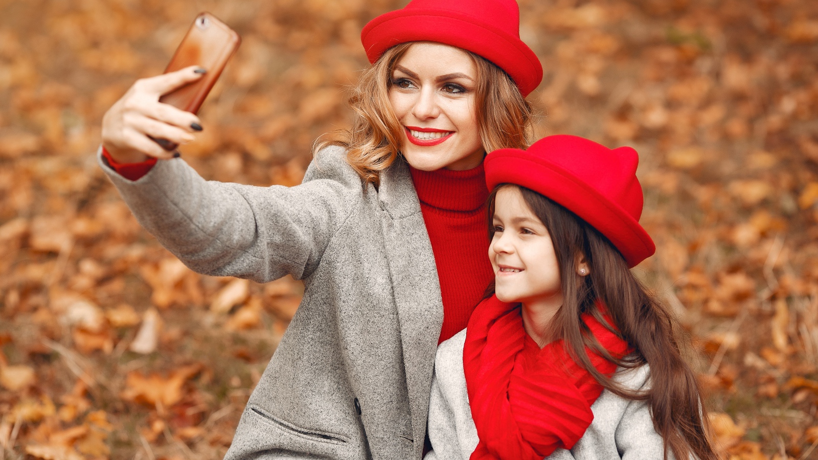 Женщина с маленькой девочкой делают селфи в лесу 