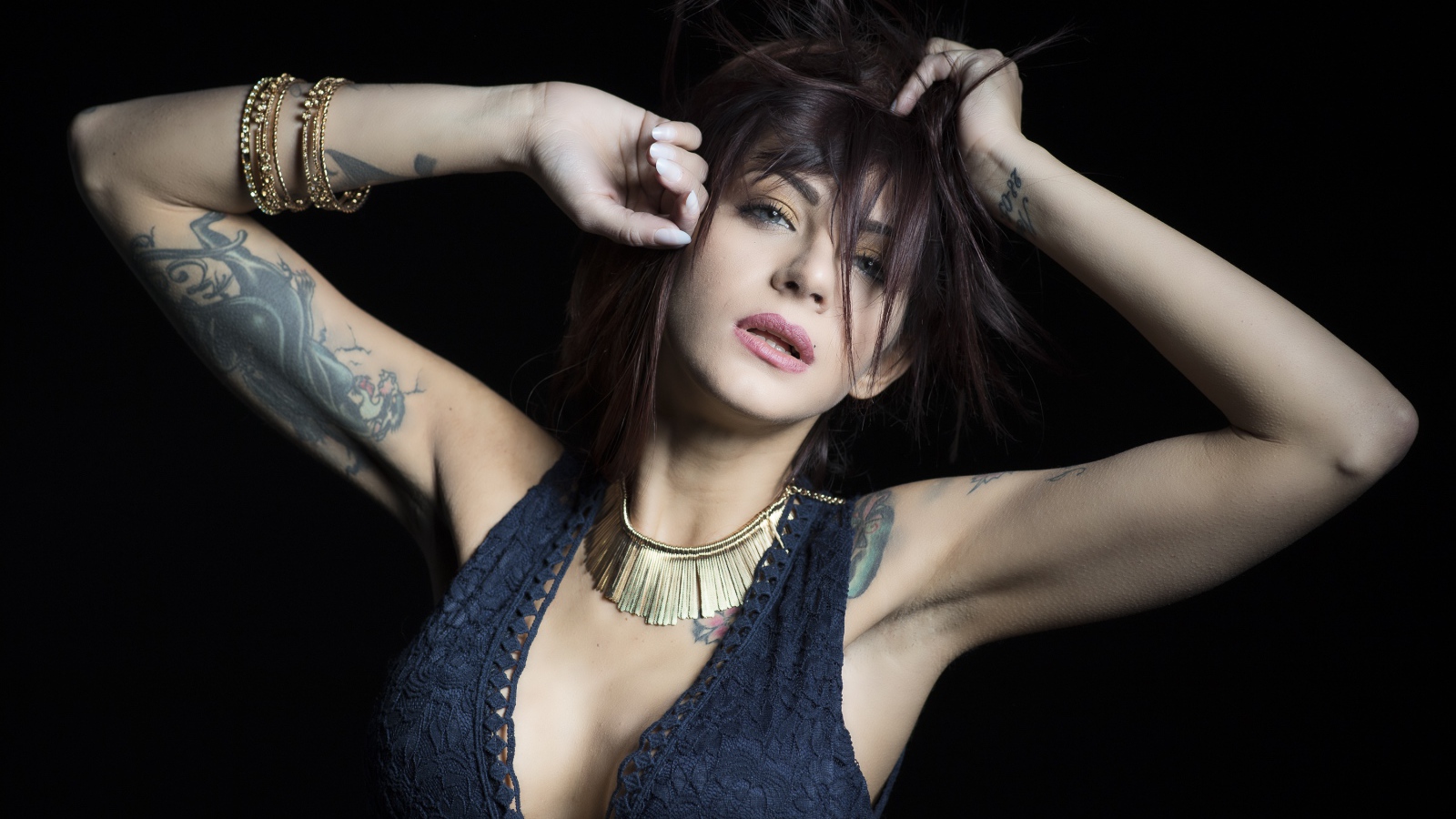 Красивая девушка в черном платье с татуировками на теле 
