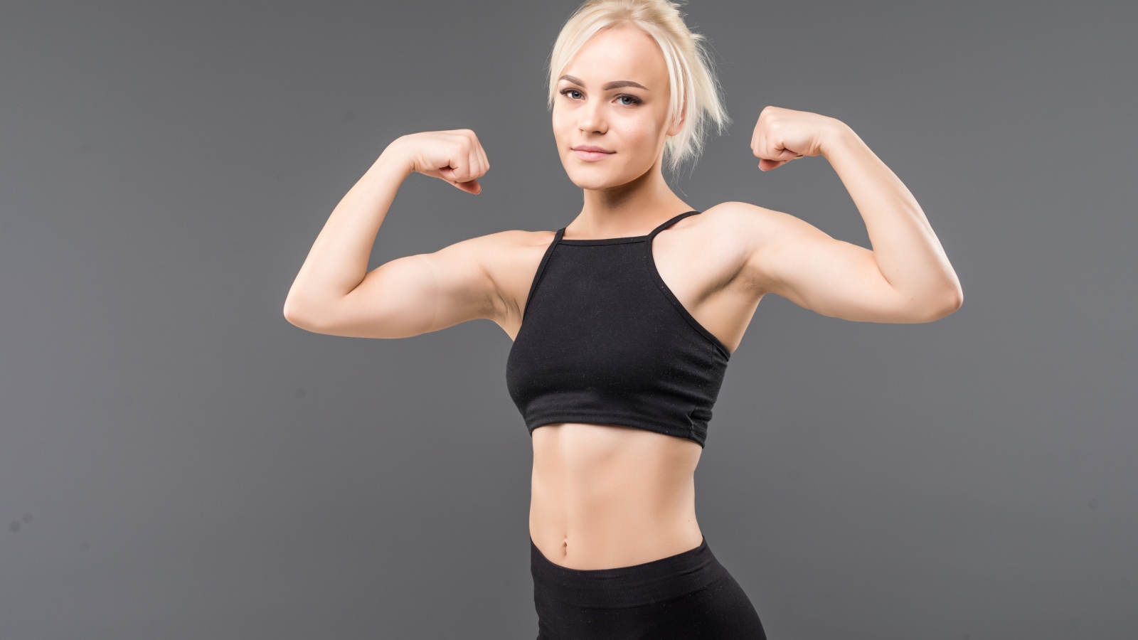 Красивая стройная спортивная девушка показывает мускулы