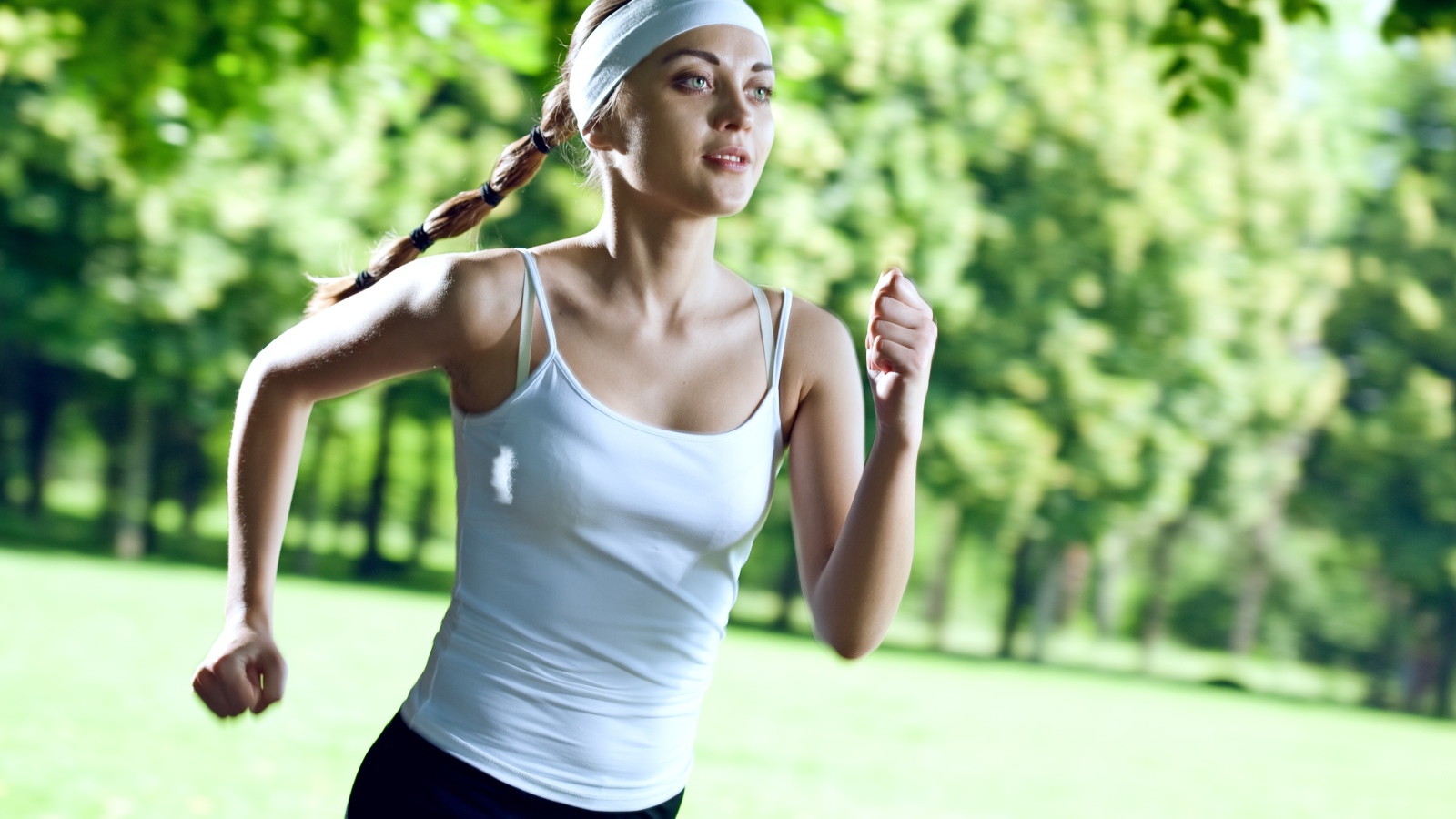 Девушка спортсменка в белой майке занимается бегом