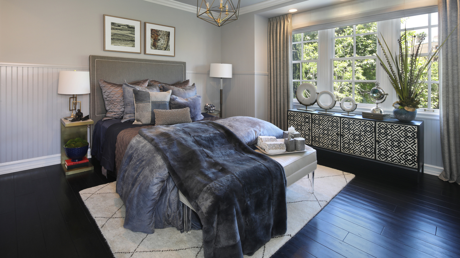 Большая кровать с мягким серым покрывалом в спальне 