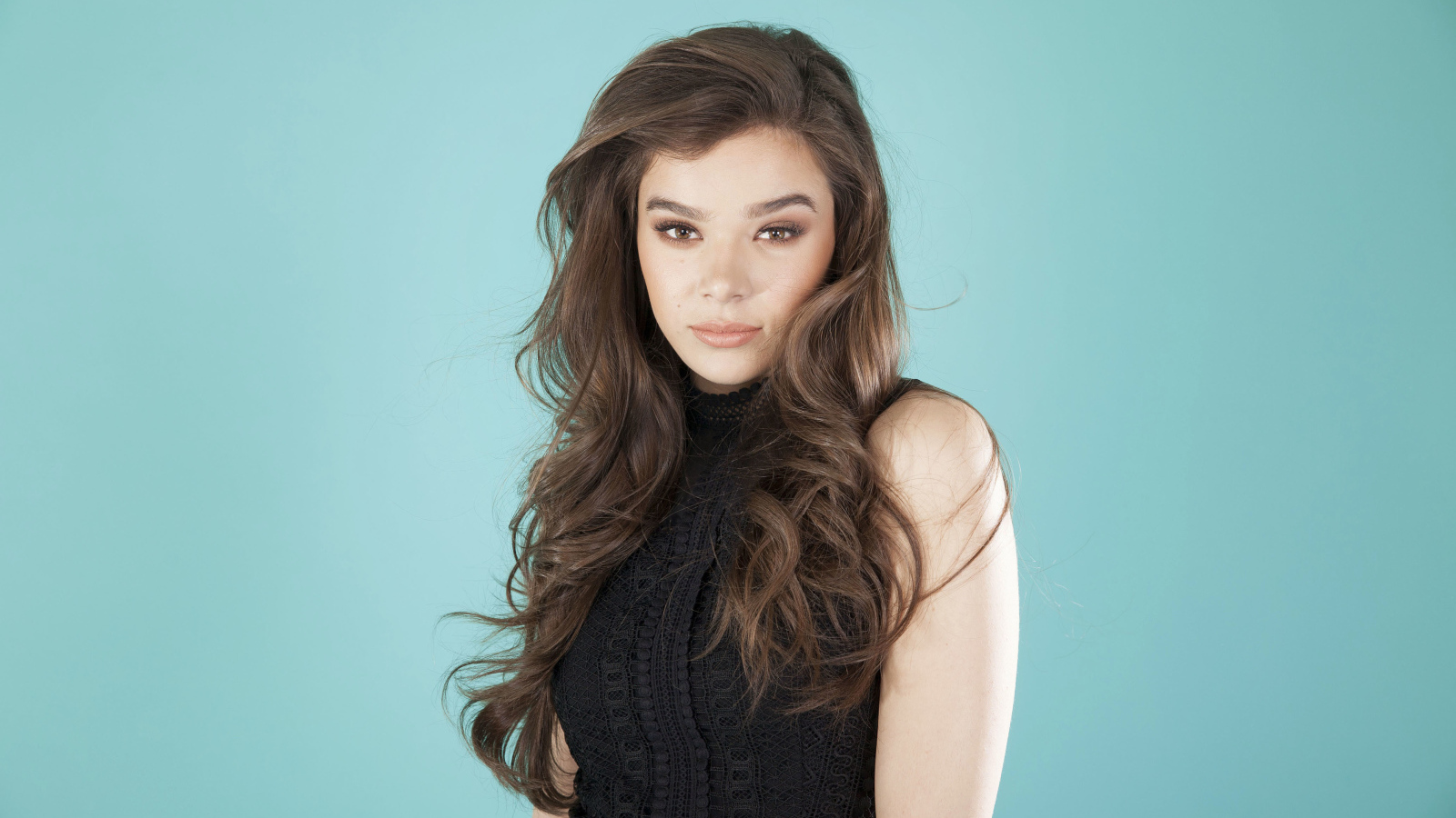 Молодая актриса Хейли Стейнфилд  в черном наряде на голубом фоне