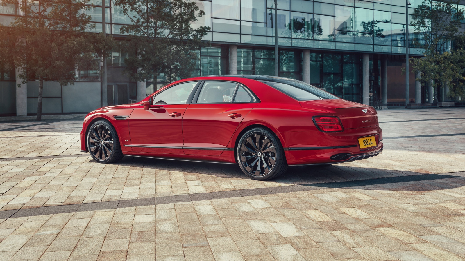Красный автомобиль Bentley Flying Spur V8 2020 года у здания 