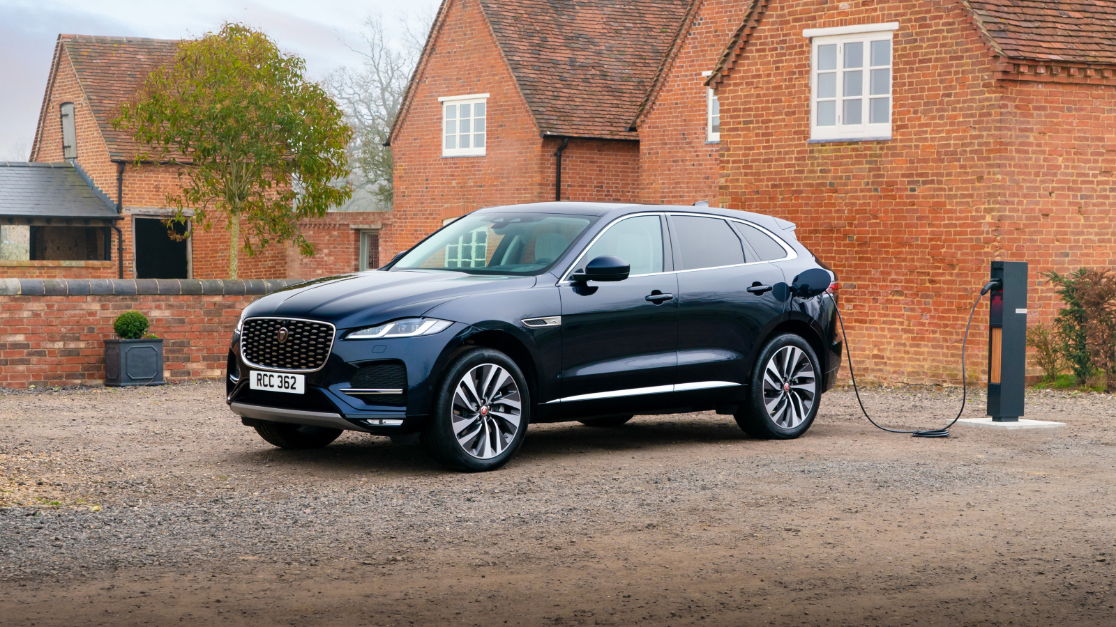 Черный дорогой автомобиль Jaguar F-Pace P400e AWD 2021 года, на заправке